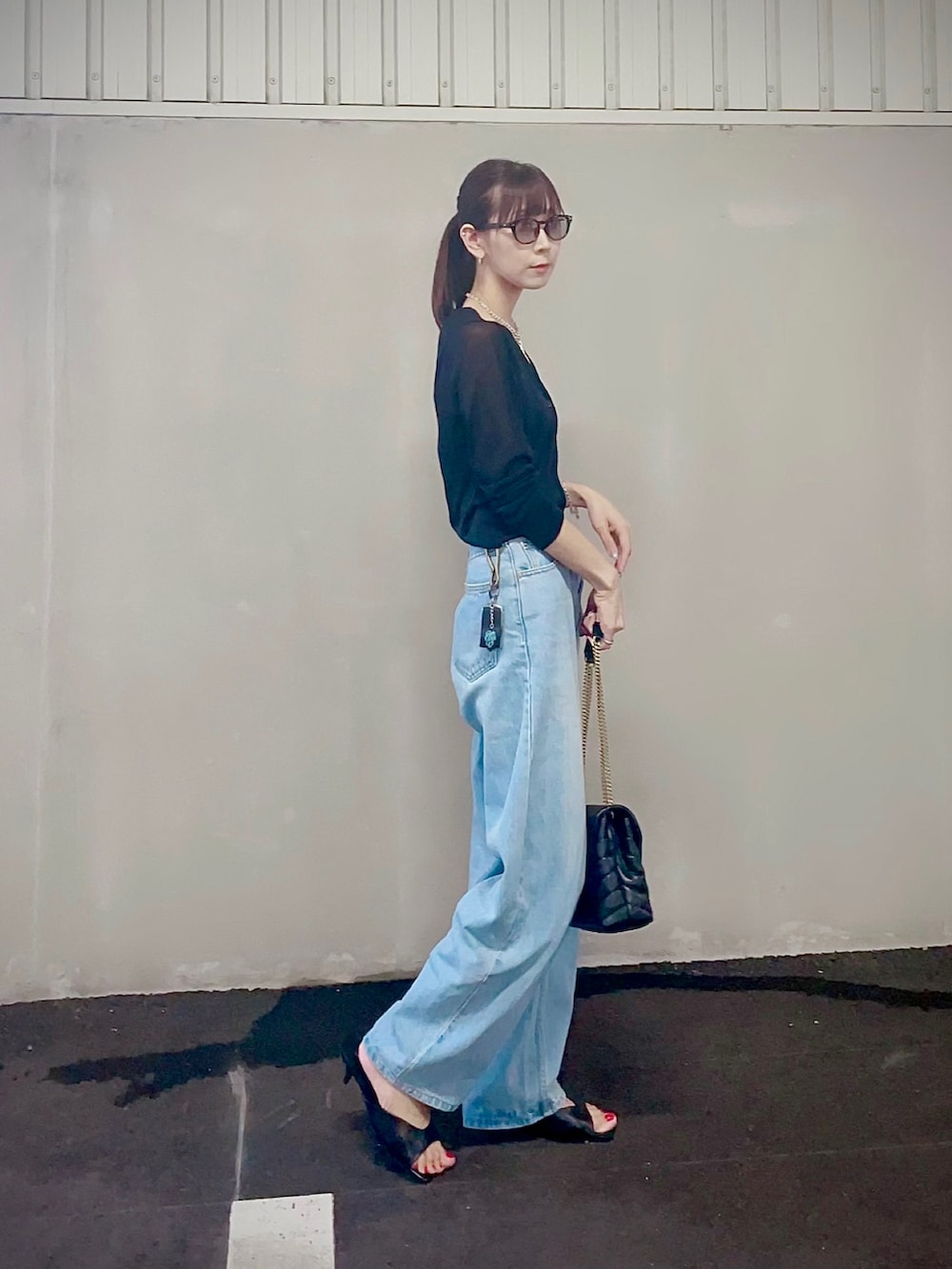 ブルー系のデニムパンツ、ブラック系のショルダーバッグ、ブラック系のカーディガン/ボレロを着用したレディースの秋コーディネートの2枚目の写真