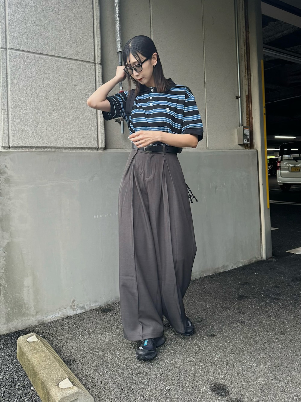 ブラック系のポロシャツ、グレー系のスラックス、ブラック系のスニーカーを着用したレディースの夏コーディネートの2枚目の写真