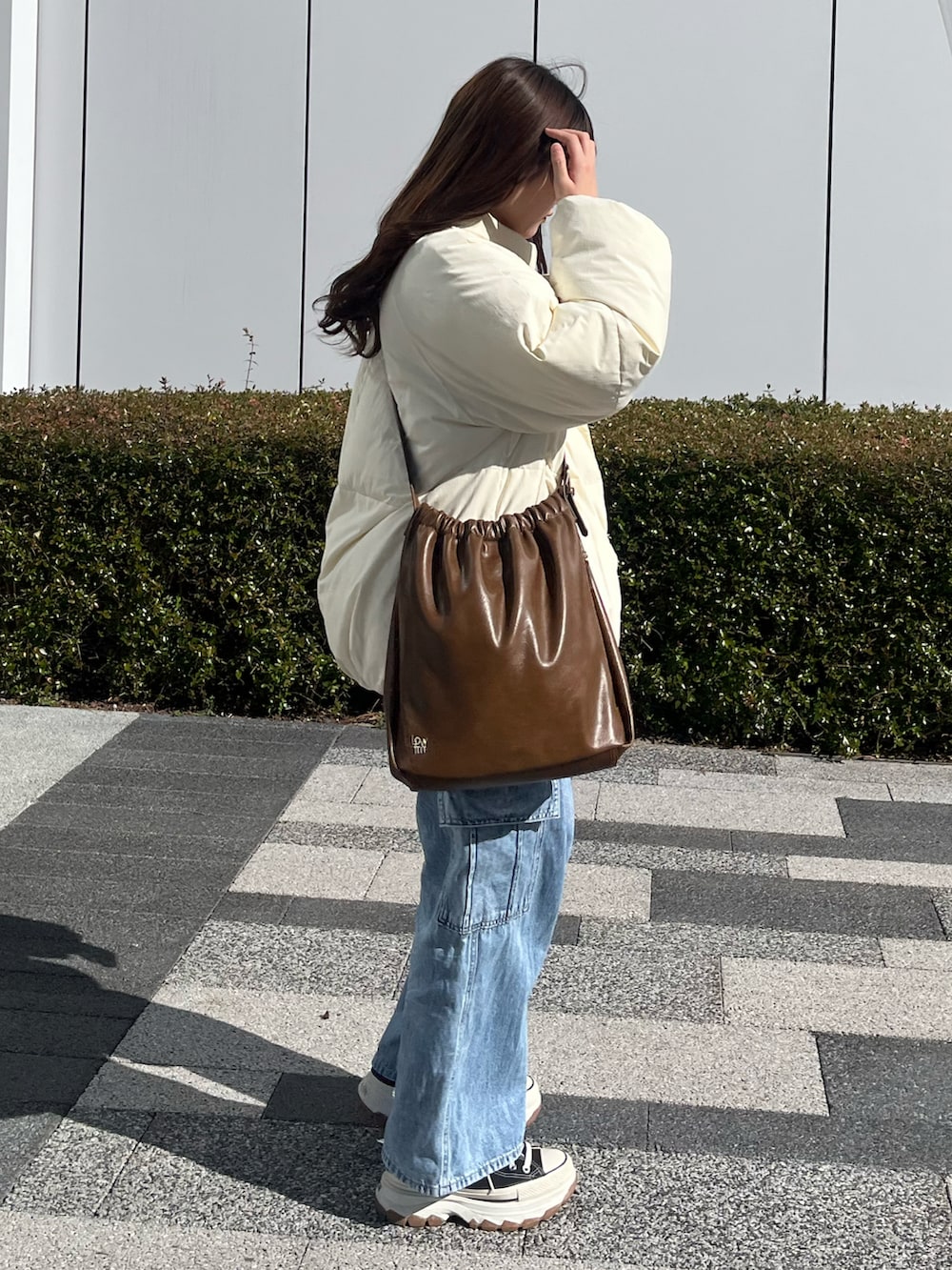 ブラック系のスニーカー、ブラウン系のショルダーバッグ、ホワイト系のブルゾンを着用したレディースの冬コーディネートの2枚目の写真