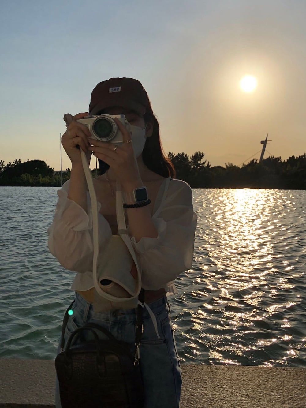 ホワイト系のスニーカー、ブルー系のデニムパンツ、ホワイト系のカーディガン/ボレロを着用したレディースの夏コーディネートの2枚目の写真