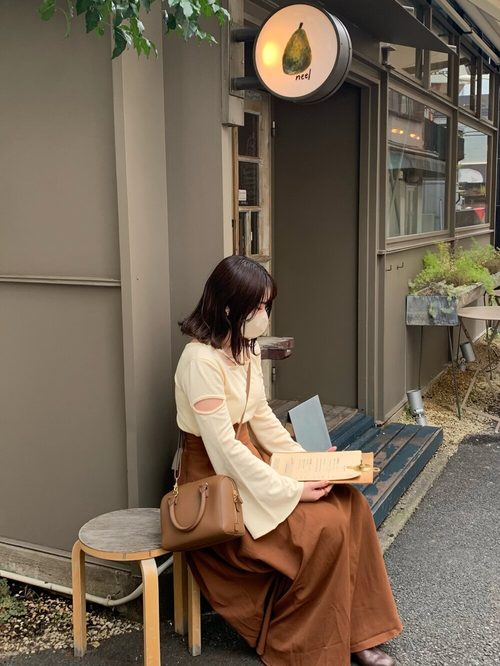 ブラウン系のスカート、ホワイト系のニット/セーター、ブラウン系のバッグを着用したレディースの秋コーディネートの2枚目の写真