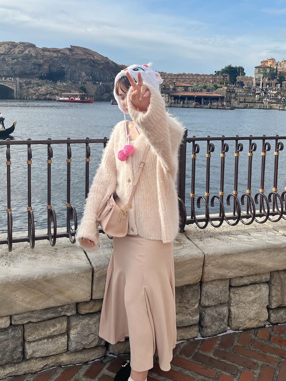 ピンク系のカーディガン/ボレロ、ホワイト系のワンピース/ドレス、ピンク系のボストンバッグを着用したレディースの秋コーディネートの2枚目の写真