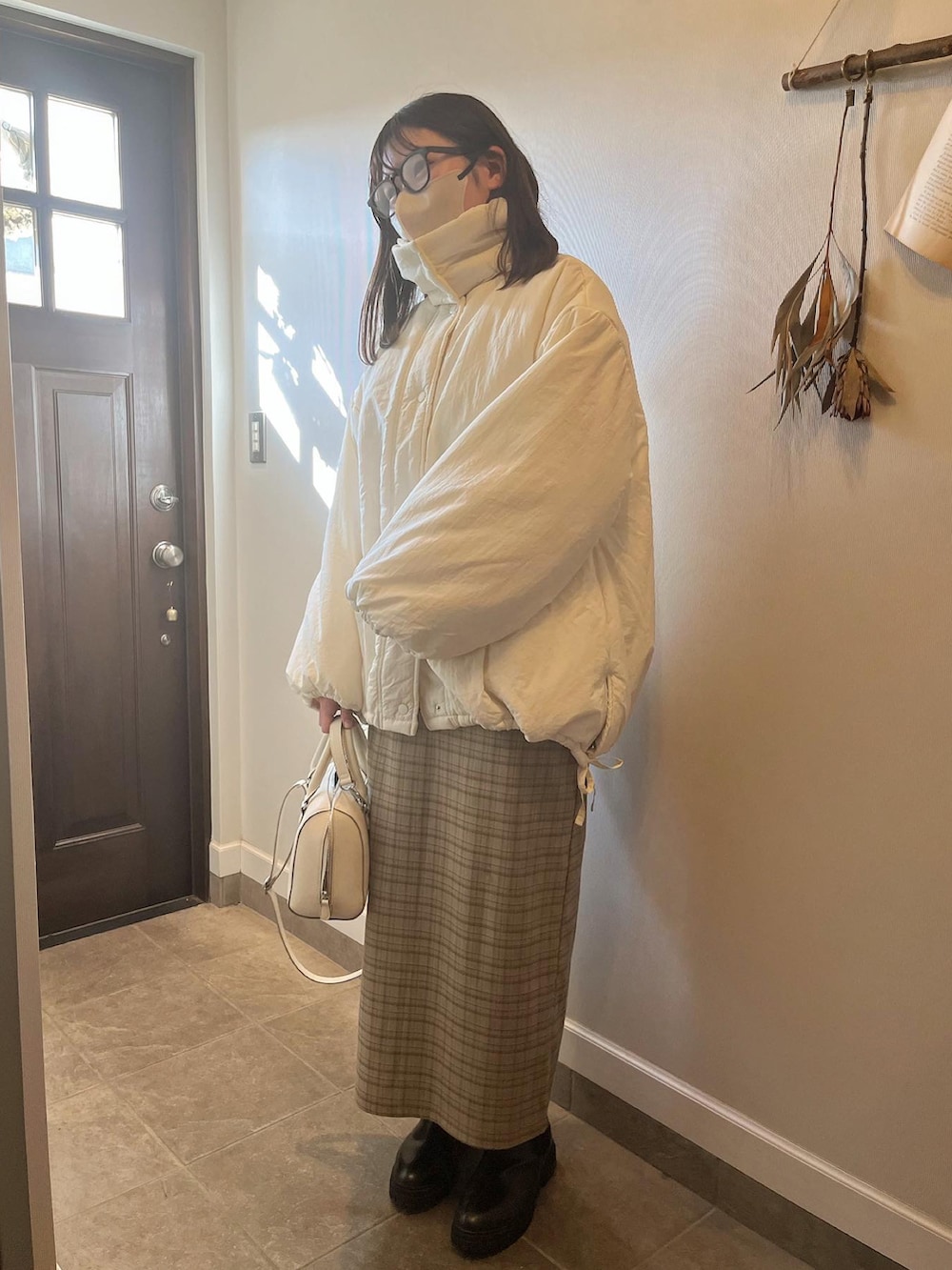 ホワイト系のダウンジャケット/コート、ベージュ系のジャンパースカート、ブラック系のブーツを着用したレディースの冬コーディネートの2枚目の写真