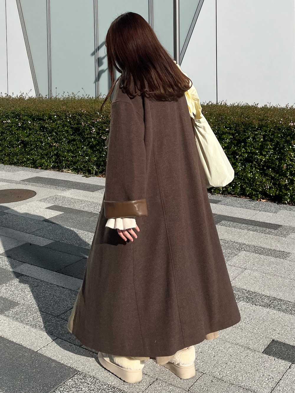 ホワイト系のブーツ、ブラウン系のその他アウター、ホワイト系のトートバッグを着用したレディースの冬コーディネートの2枚目の写真