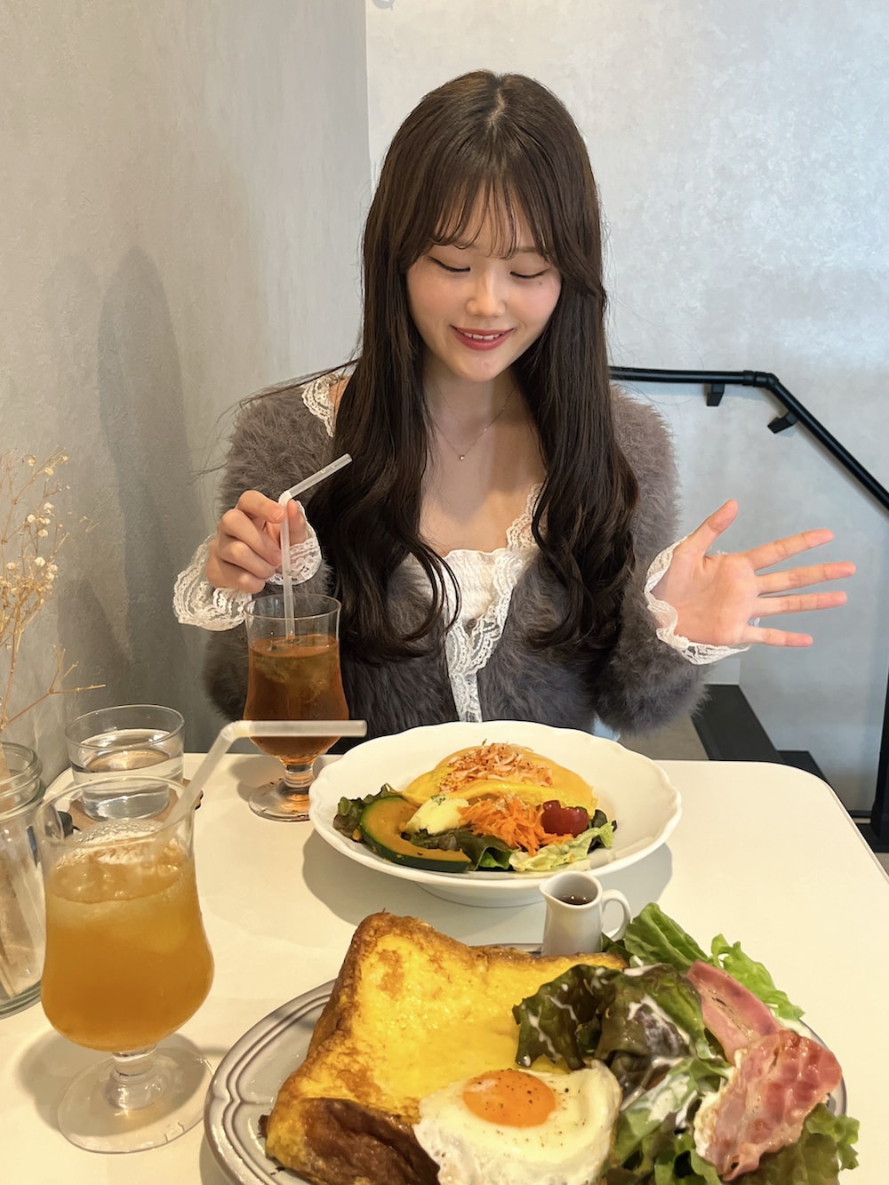 ブルー系のデニムパンツ、グレー系のカーディガン/ボレロ、ホワイト系のキャミソールを着用したレディースの春コーディネートの2枚目の写真