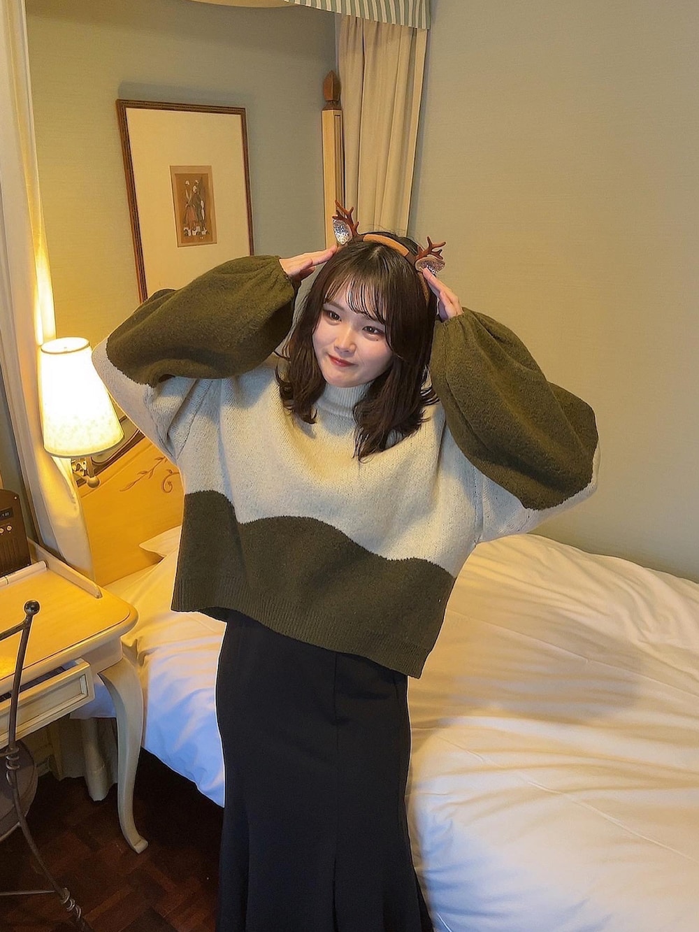 グリーン系のニット/セーター、ブラック系のスカート、ブラック系のブーツを着用したレディースの冬コーディネートの3枚目の写真