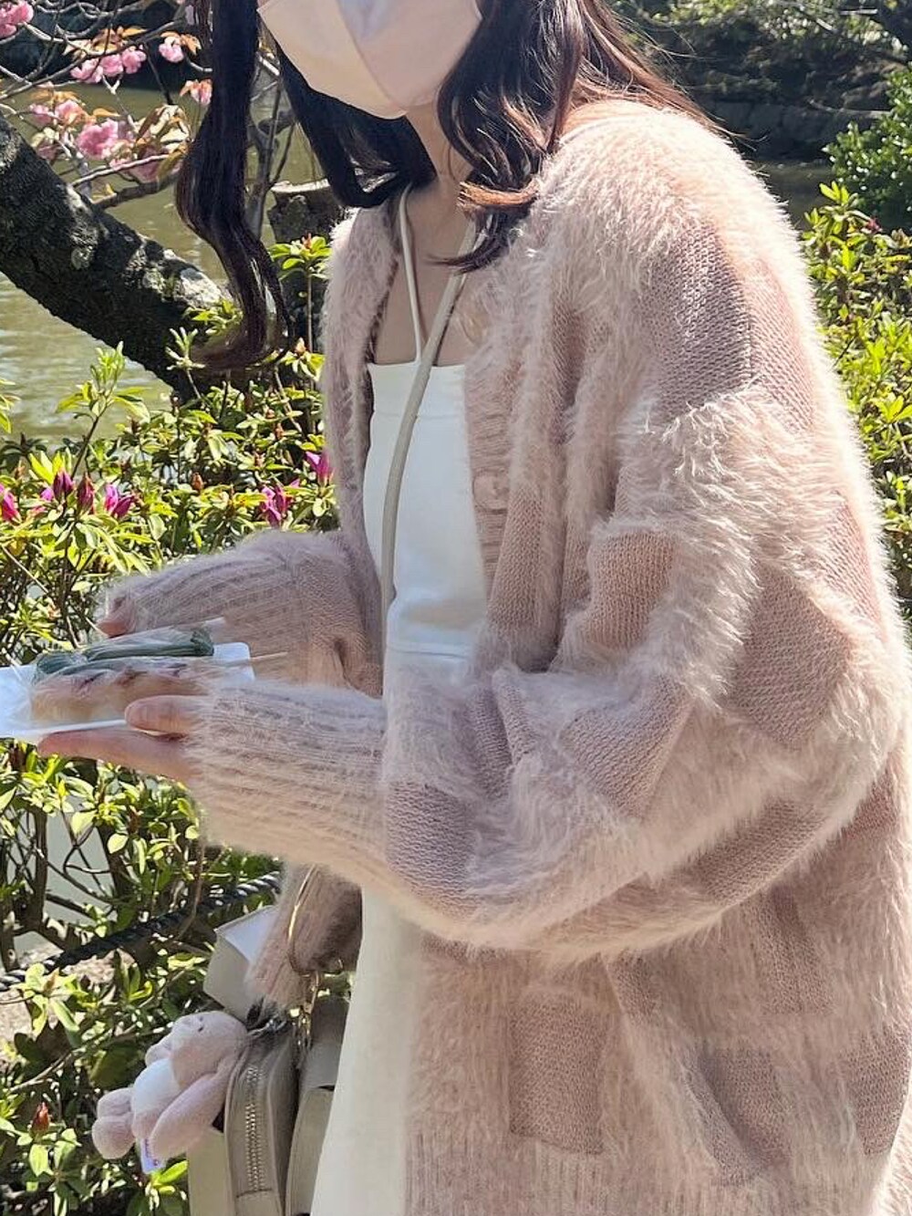 ピンク系のニット/セーター、ホワイト系のショルダーバッグ、ホワイト系のワンピースを着用したレディースの春コーディネートの2枚目の写真