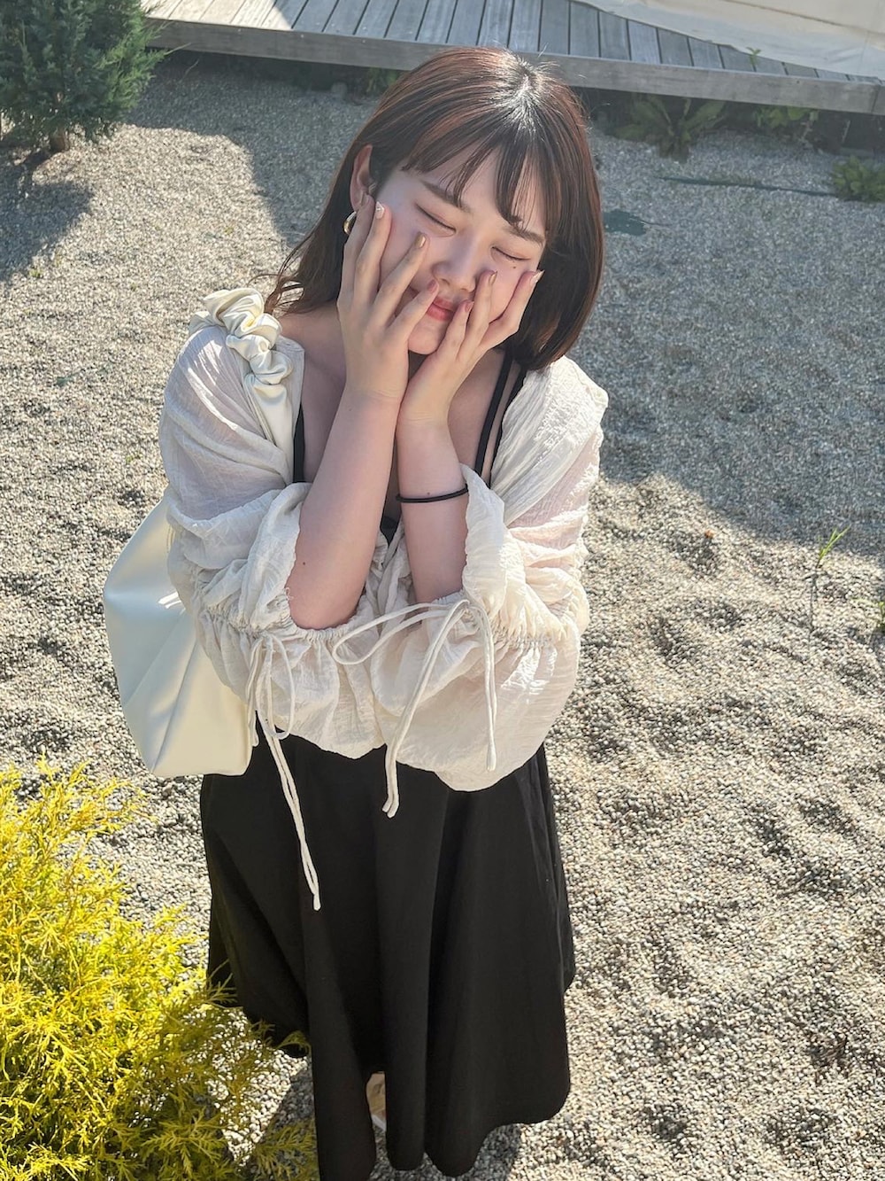 ブラック系のワンピース、ホワイト系のシャツ/ブラウス、ベージュ系のサンダルを着用したレディースの夏コーディネートの3枚目の写真