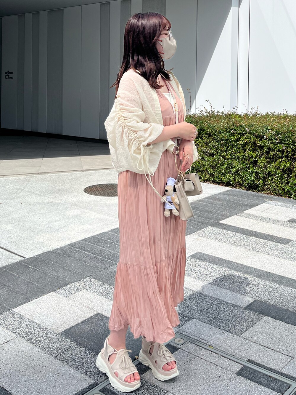 ベージュ系のワンピース、ホワイト系のショルダーバッグ、ベージュ系のサンダルを着用したレディースの春コーディネートの2枚目の写真