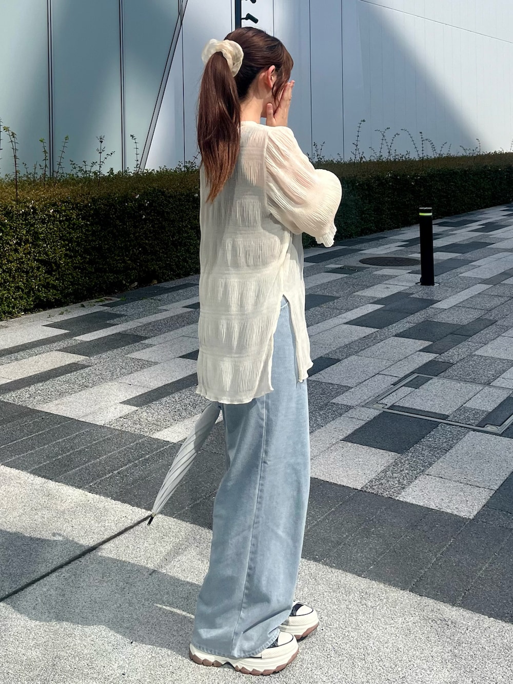 ブルー系のデニムパンツ、ブラック系のスニーカー、ホワイト系のシャツ/ブラウスを着用したレディースの夏コーディネートの2枚目の写真