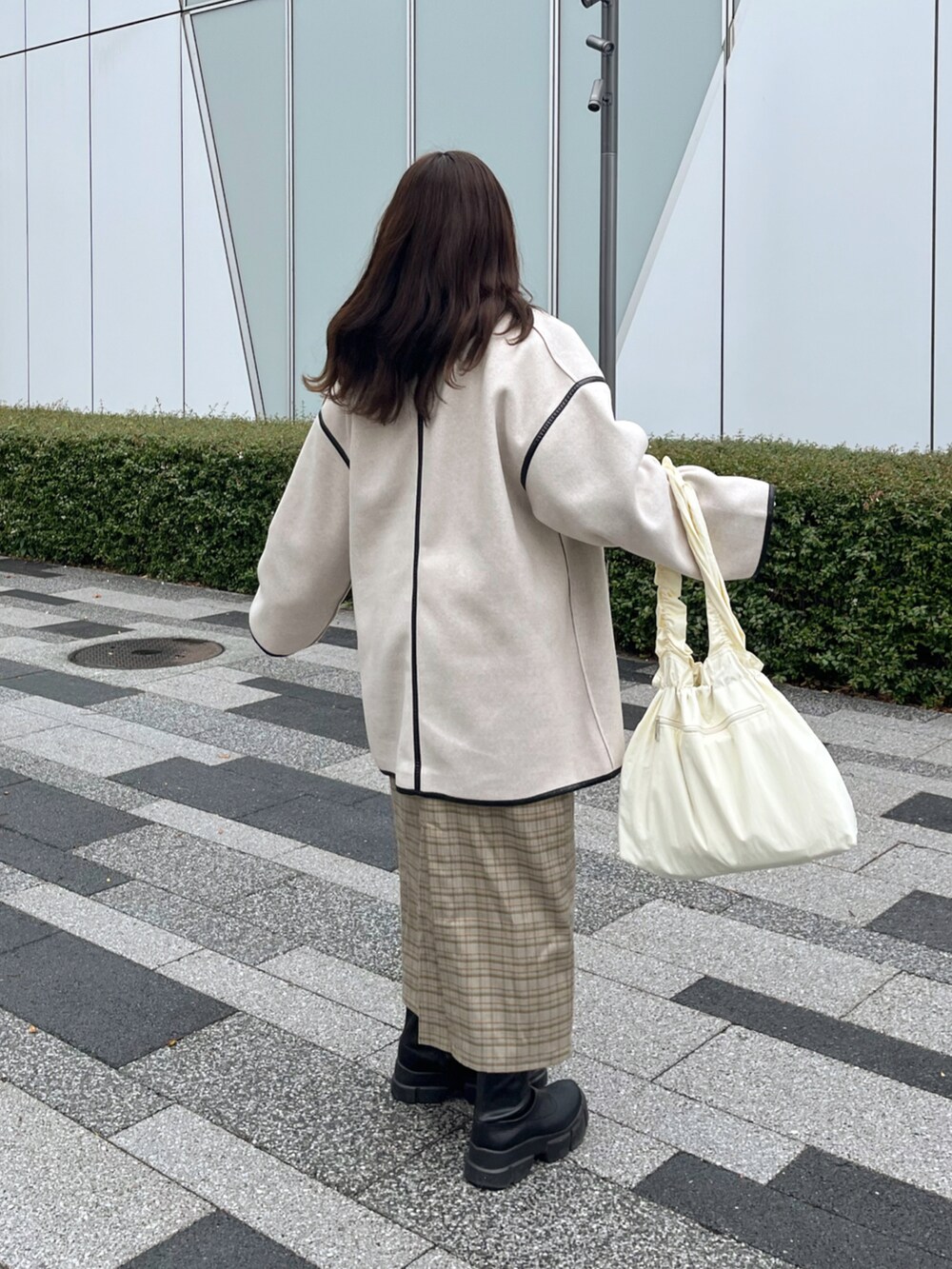 ホワイト系のその他アウター、ホワイト系のトートバッグ、ベージュ系のジャンパースカートを着用したレディースの秋コーディネートの2枚目の写真