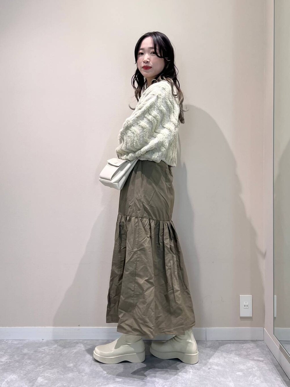 ホワイト系のショルダーバッグ、ホワイト系のブーツ、ホワイト系のニット/セーターを着用したレディースの冬コーディネートの3枚目の写真