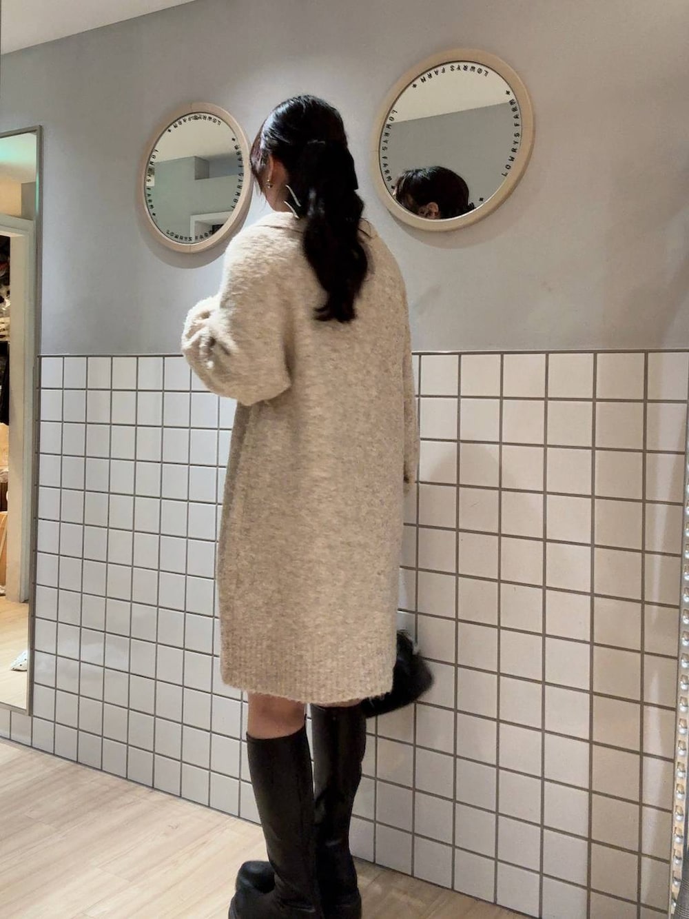 ブラック系のブーツ、ホワイト系のワンピース、ブラック系のショルダーバッグを着用したレディースの冬コーディネートの3枚目の写真