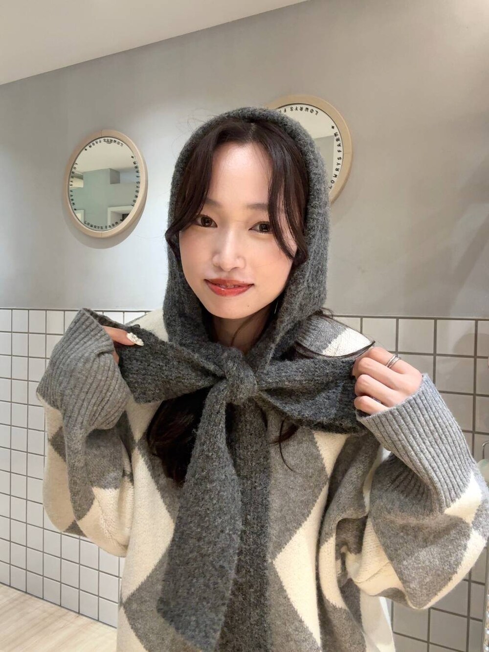 グレー系のニット/セーター、グレー系のマフラーを着用したレディースの秋コーディネートの2枚目の写真