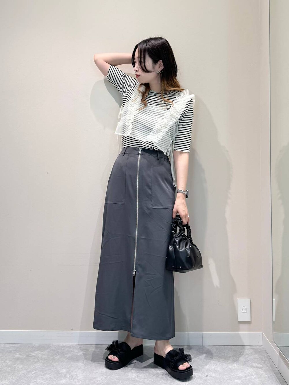 ブラック系のハンドバッグ、ブラック系のサンダル、ホワイト系のTシャツ/カットソーを着用したレディースの夏コーディネートの4枚目の写真