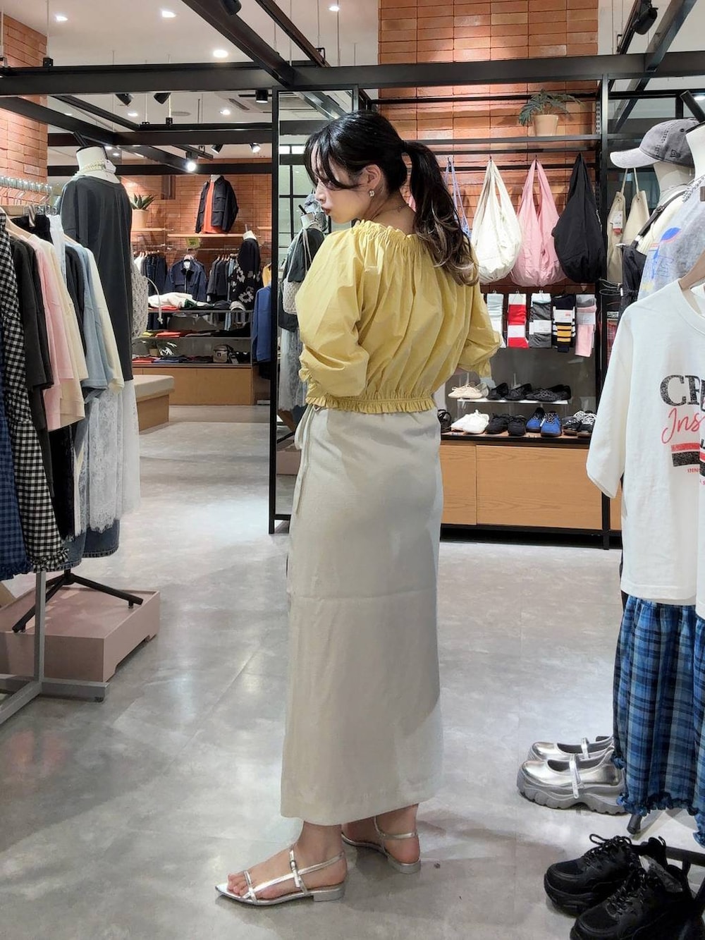 ホワイト系のスカート、ブラック系のトートバッグ、シルバー系のサンダルを着用したレディースの春コーディネートの2枚目の写真