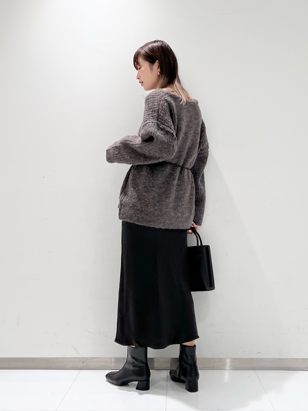 ブラック系のショルダーバッグ、ブラック系のスカート、ブラック系のブーツを着用したレディースの冬コーディネートの2枚目の写真