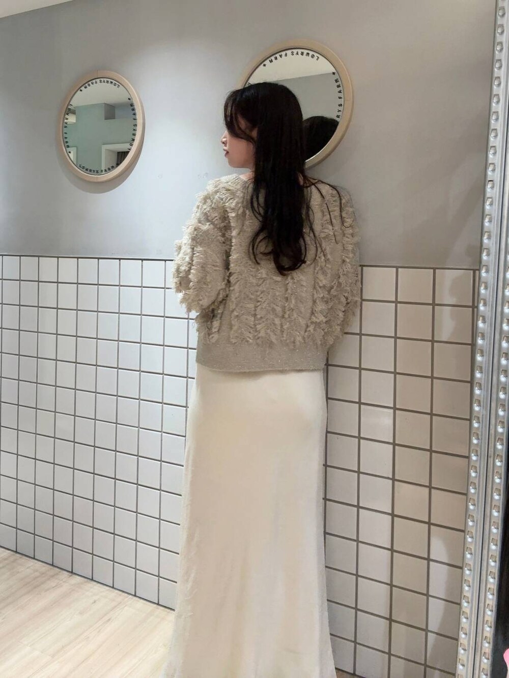 ホワイト系のスカート、ベージュ系のカーディガン/ボレロ、ブラック系のボストンバッグを着用したレディースの秋コーディネートの2枚目の写真