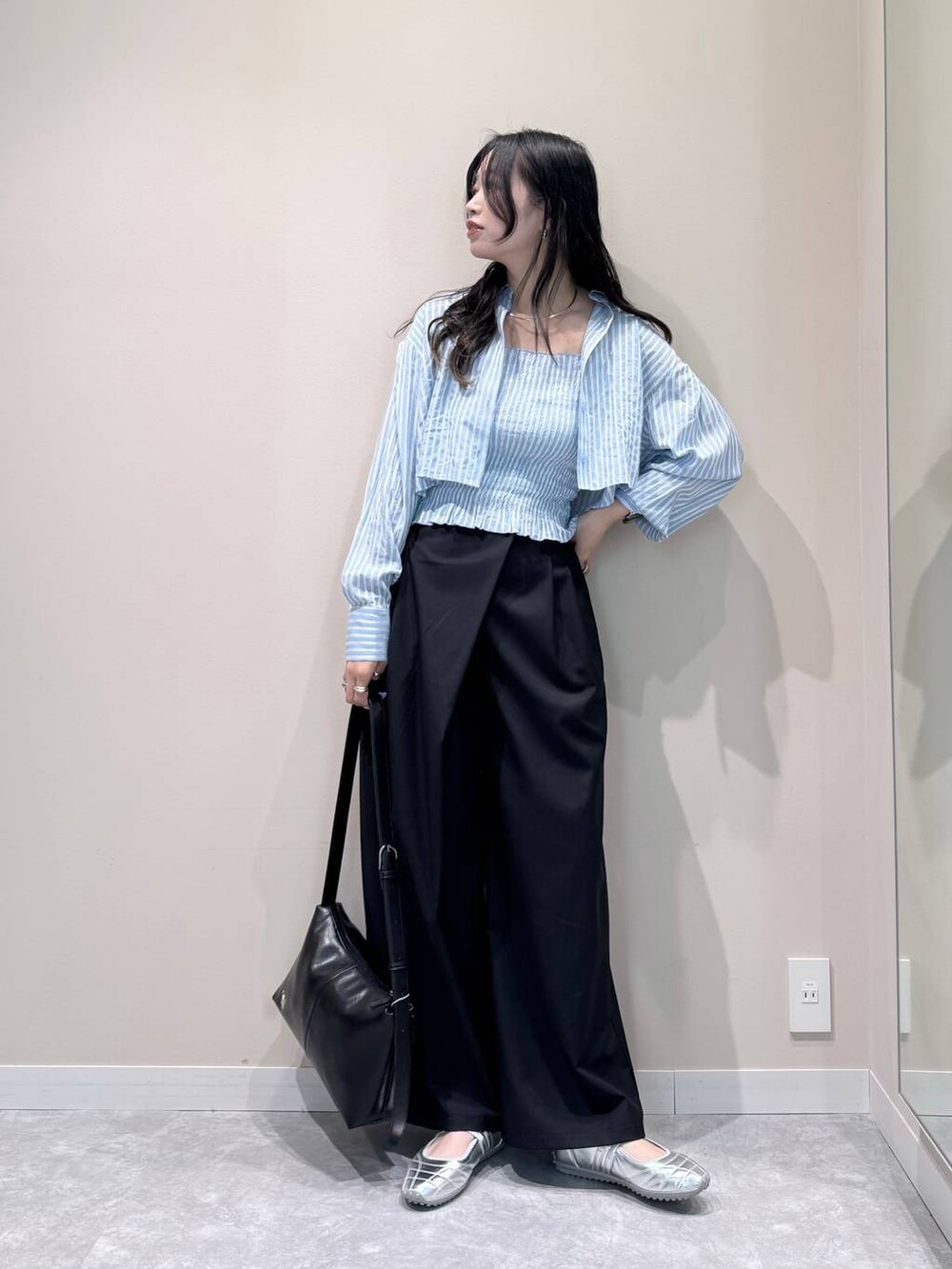 シルバー系のスニーカー、ブラック系のスラックス、ブラック系のショルダーバッグを着用したレディースの春コーディネートの2枚目の写真