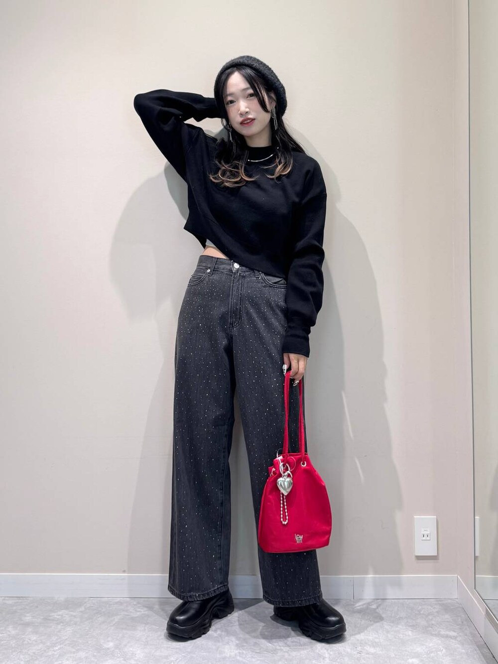 ブラック系のブーツ、ブラック系のデニムパンツ、レッド系のハンドバッグを着用したレディースの秋コーディネートの3枚目の写真