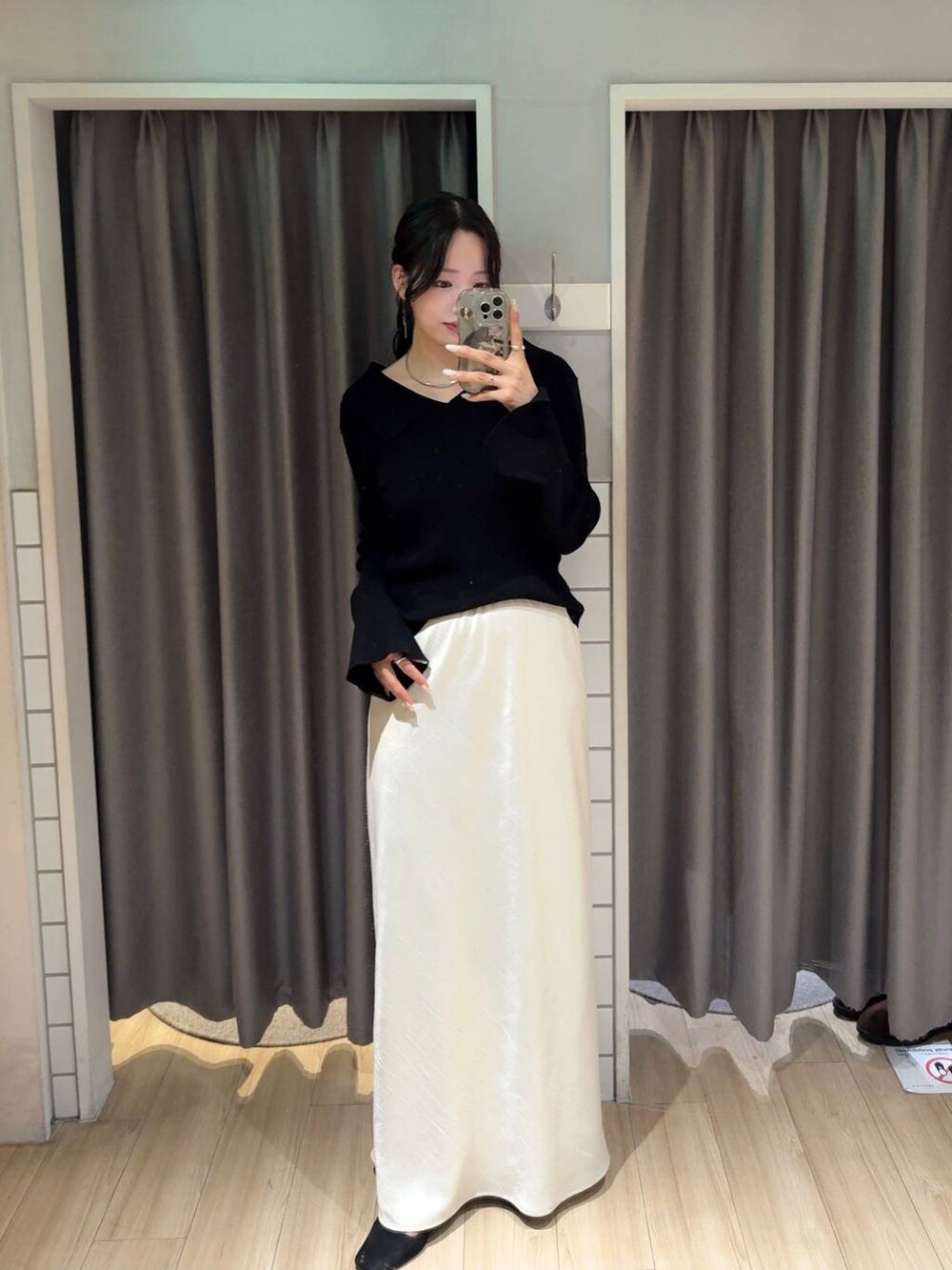 ホワイト系のスカート、ブラック系のニット/セーター、シルバー系のチョーカーを着用したレディースの秋コーディネートの2枚目の写真