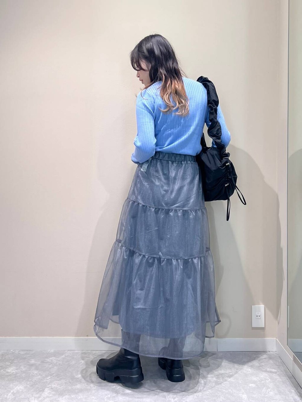 ブラック系のブーツ、ブラック系のショルダーバッグ、ブルー系のニット/セーターを着用したレディースの冬コーディネートの2枚目の写真