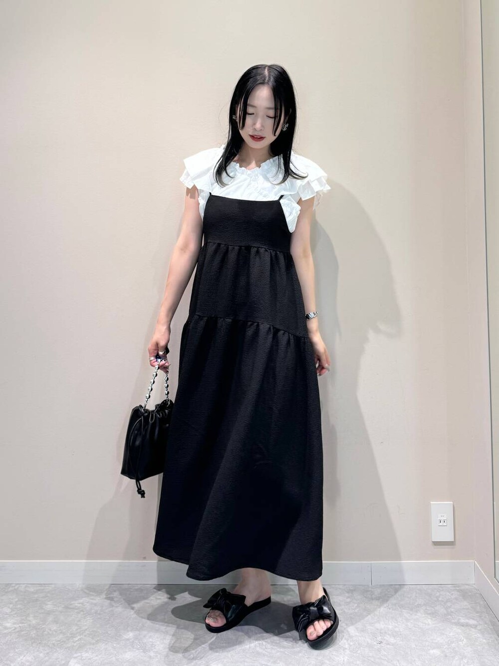 ブラック系のワンピース、ブラック系のショルダーバッグ、ブラック系のサンダルを着用したレディースの夏コーディネートの2枚目の写真