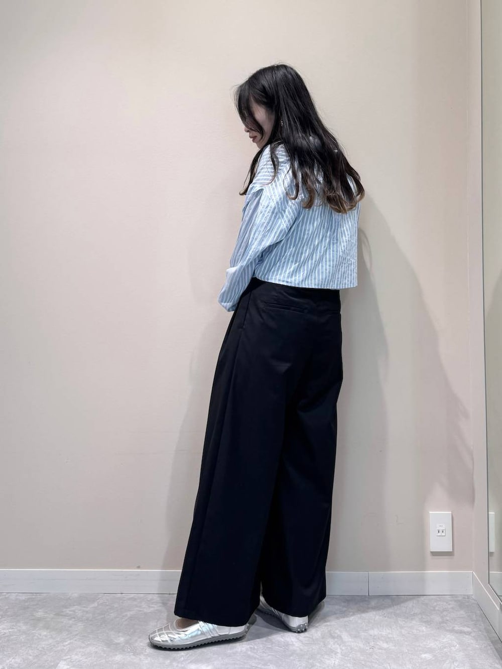 シルバー系のスニーカー、ブラック系のスラックス、ブラック系のショルダーバッグを着用したレディースの春コーディネートの3枚目の写真