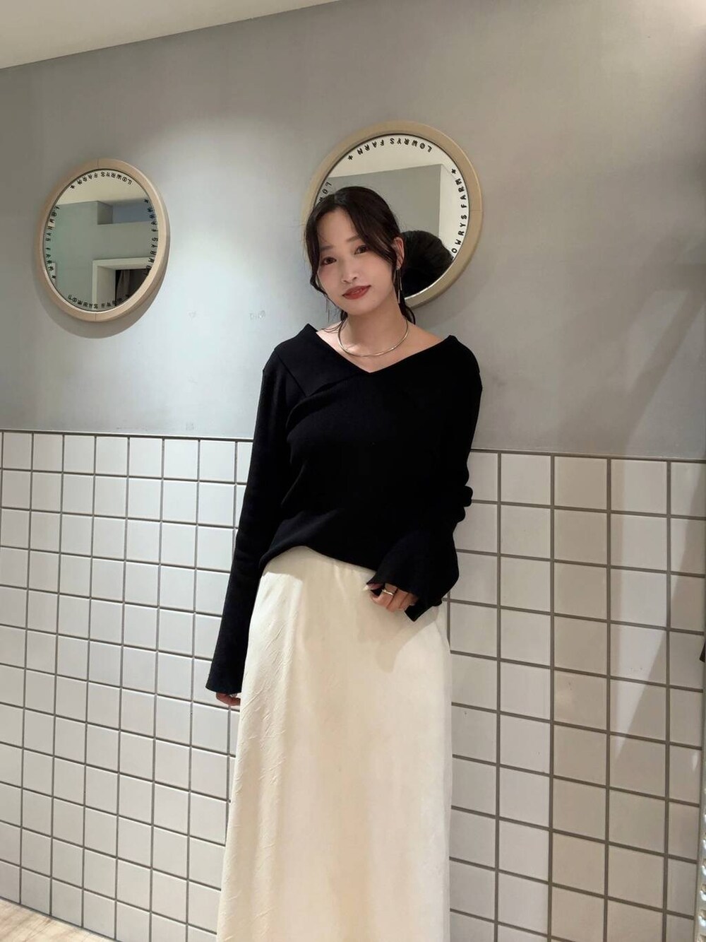 ホワイト系のスカート、ブラック系のニット/セーター、シルバー系のチョーカーを着用したレディースの秋コーディネートの3枚目の写真