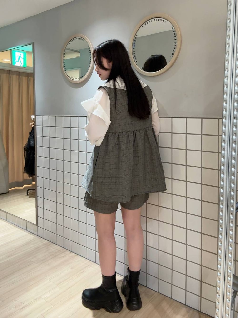 ブラック系のブーツ、その他のベスト、ブラウン系のボストンバッグを着用したレディースの秋コーディネートの2枚目の写真