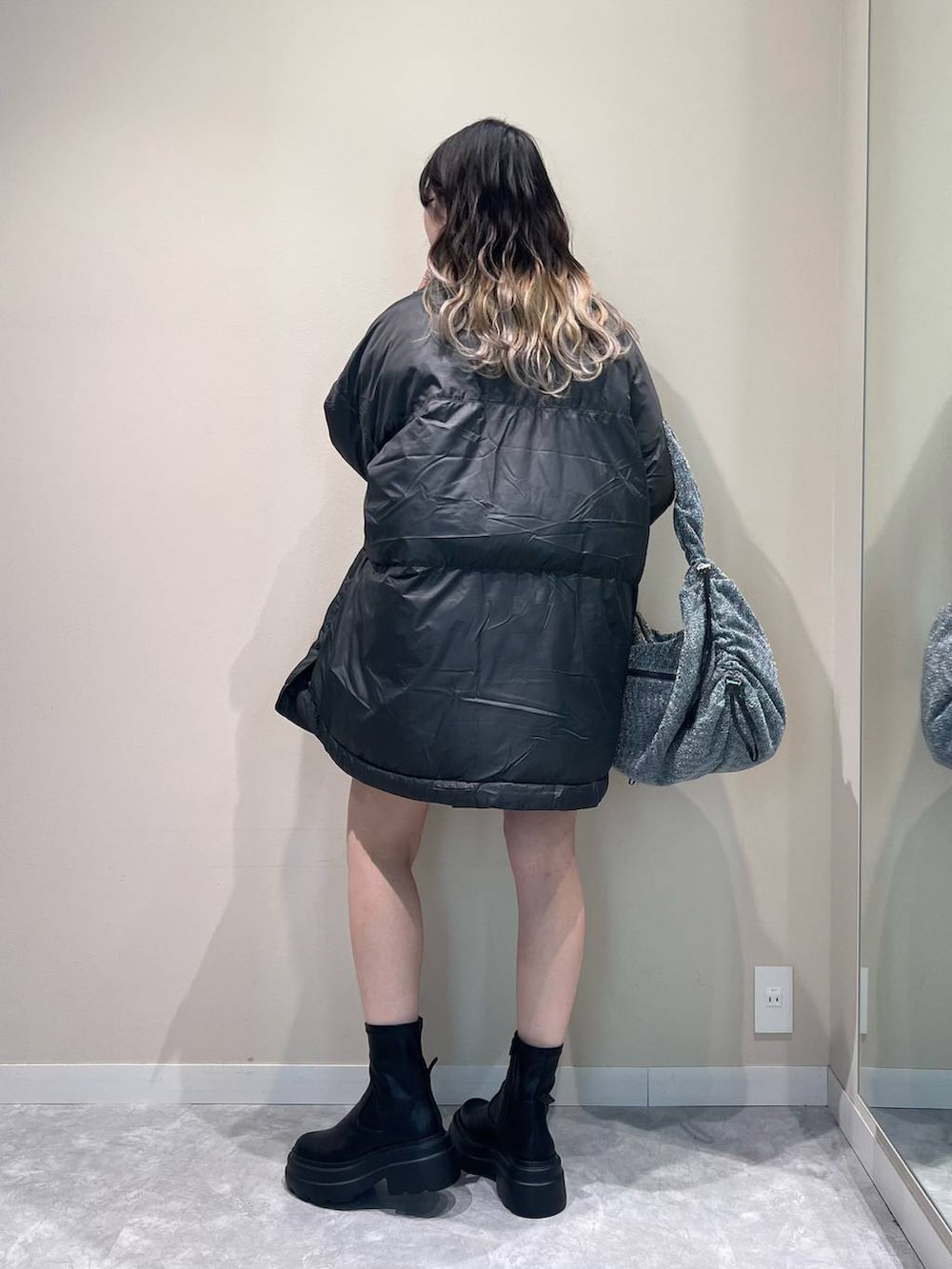 グレー系のポンチョ、シルバー系のショルダーバッグ、ブラック系のブーツを着用したレディースの秋コーディネートの3枚目の写真