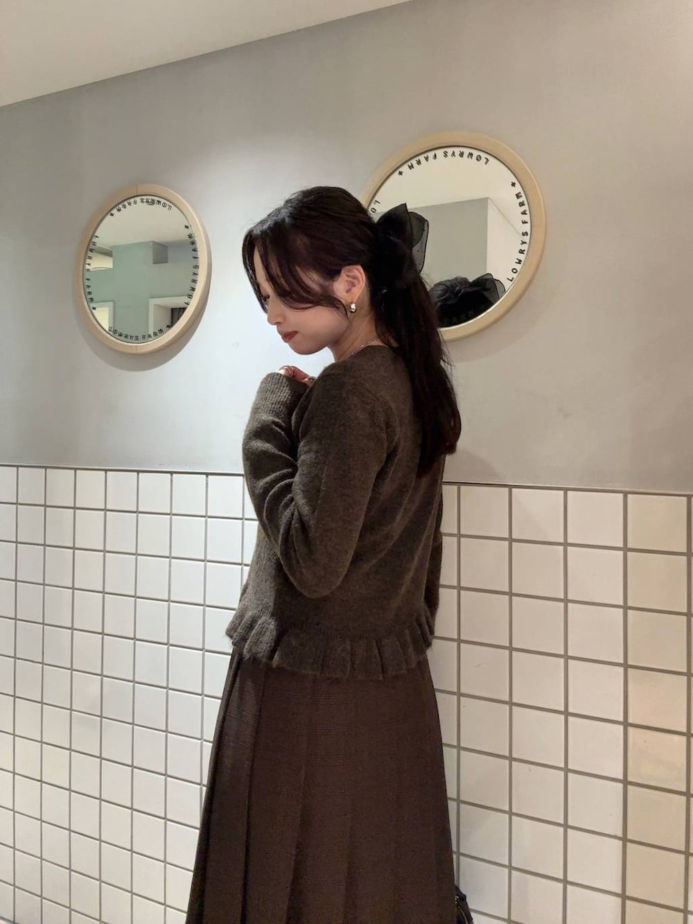 ブラウン系のスカート、ブラウン系のニット/セーター、シルバー系のネックレスを着用したレディースの秋コーディネートの2枚目の写真