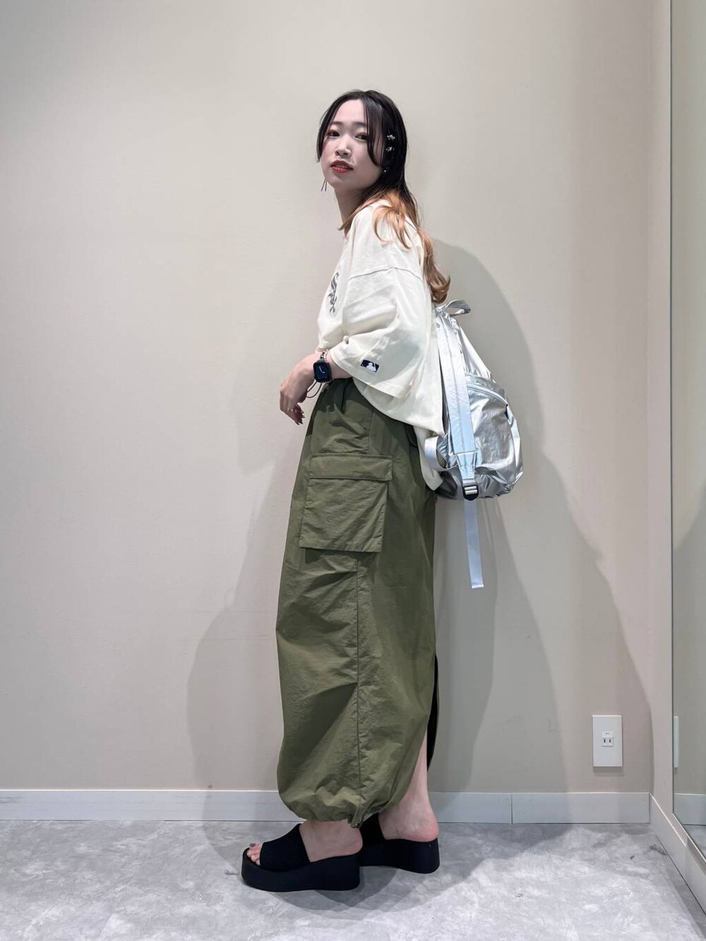ブラック系のサンダル、シルバー系のバックパック/リュック、グリーン系のスカートを着用したレディースの春コーディネートの4枚目の写真