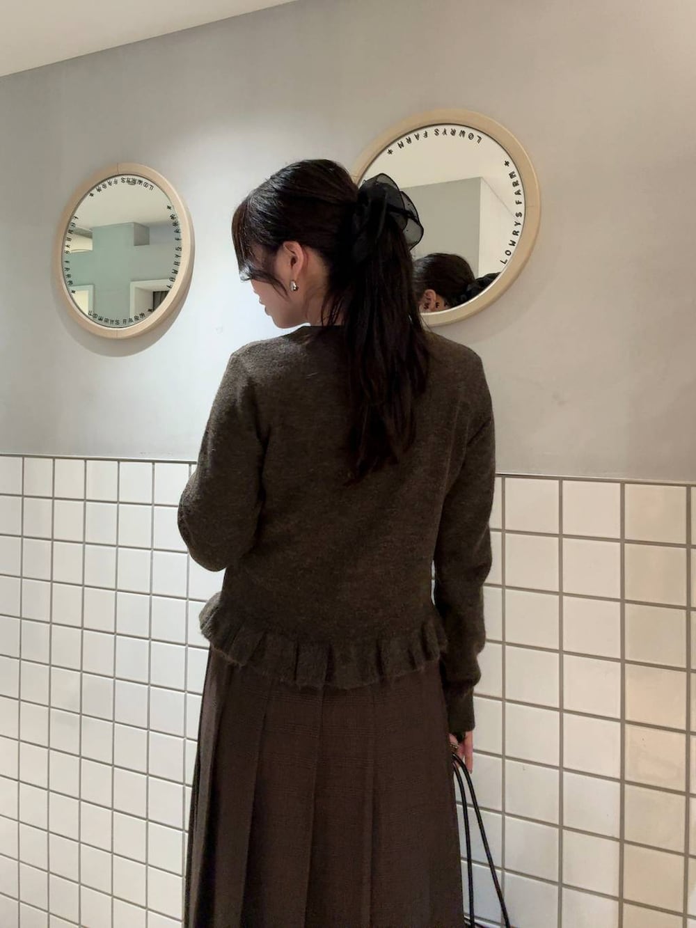 ブラウン系のスカート、ブラウン系のニット/セーター、シルバー系のネックレスを着用したレディースの秋コーディネートの4枚目の写真