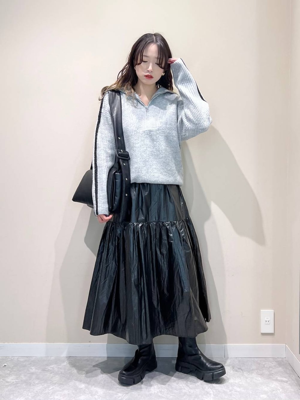 ブラック系のブーツ、ブラック系のショルダーバッグ、ブラック系のスカートを着用したレディースの冬コーディネートの2枚目の写真