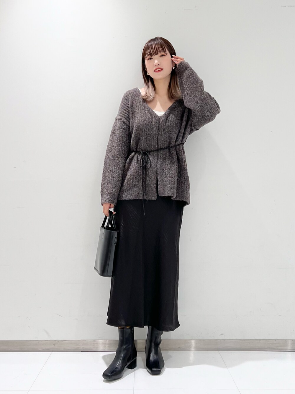 ブラック系のショルダーバッグ、ブラック系のスカート、ブラック系のブーツを着用したレディースの冬コーディネートの4枚目の写真