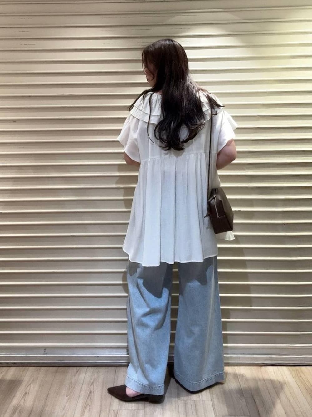 ブルー系のデニムパンツ、ブラウン系のトートバッグ、ブラウン系のサンダルを着用したレディースの夏コーディネートの2枚目の写真