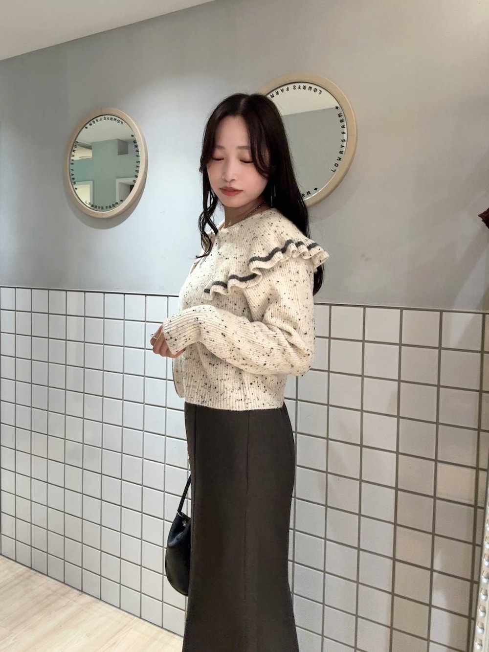 ブラック系のショルダーバッグ、グレー系のスカート、ベージュ系のニット/セーターを着用したレディースの秋コーディネートの3枚目の写真