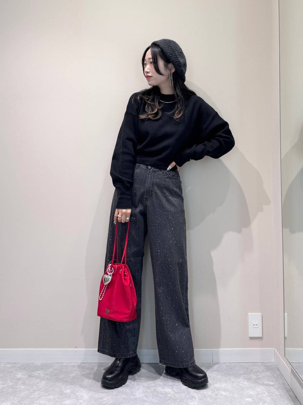 ブラック系のブーツ、ブラック系のデニムパンツ、レッド系のハンドバッグを着用したレディースの秋コーディネートの2枚目の写真