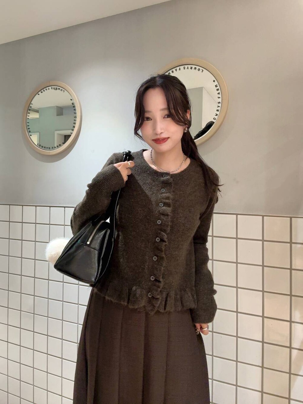 ブラウン系のスカート、ブラウン系のニット/セーター、シルバー系のネックレスを着用したレディースの秋コーディネートの3枚目の写真