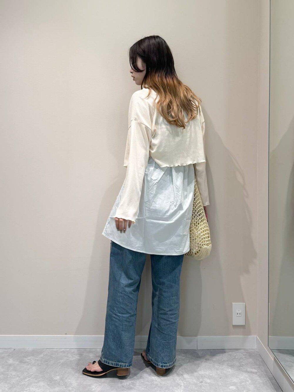 ベージュ系のショルダーバッグ、ホワイト系のシャツ/ブラウス、ブルー系のデニムパンツを着用したレディースの夏コーディネートの2枚目の写真