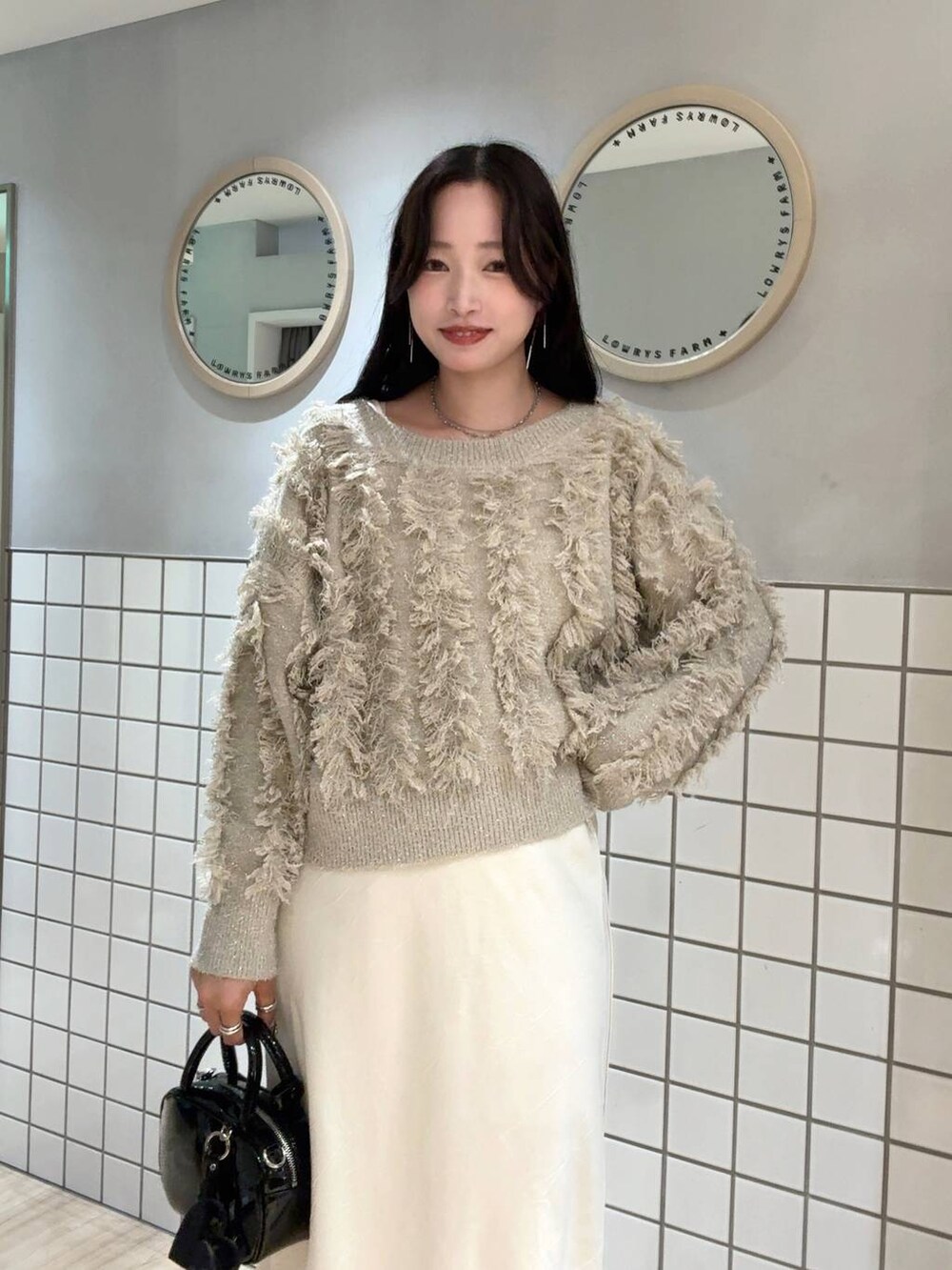 ホワイト系のスカート、ベージュ系のカーディガン/ボレロ、ブラック系のボストンバッグを着用したレディースの秋コーディネートの3枚目の写真