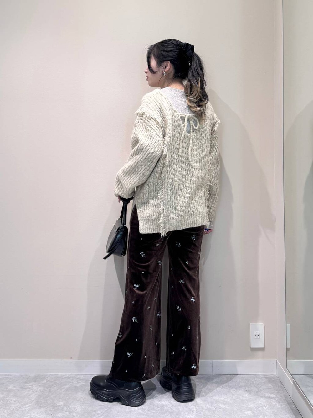 ホワイト系のニット/セーター、ホワイト系のTシャツ/カットソー、ブラック系のショルダーバッグを着用したレディースの冬コーディネートの4枚目の写真