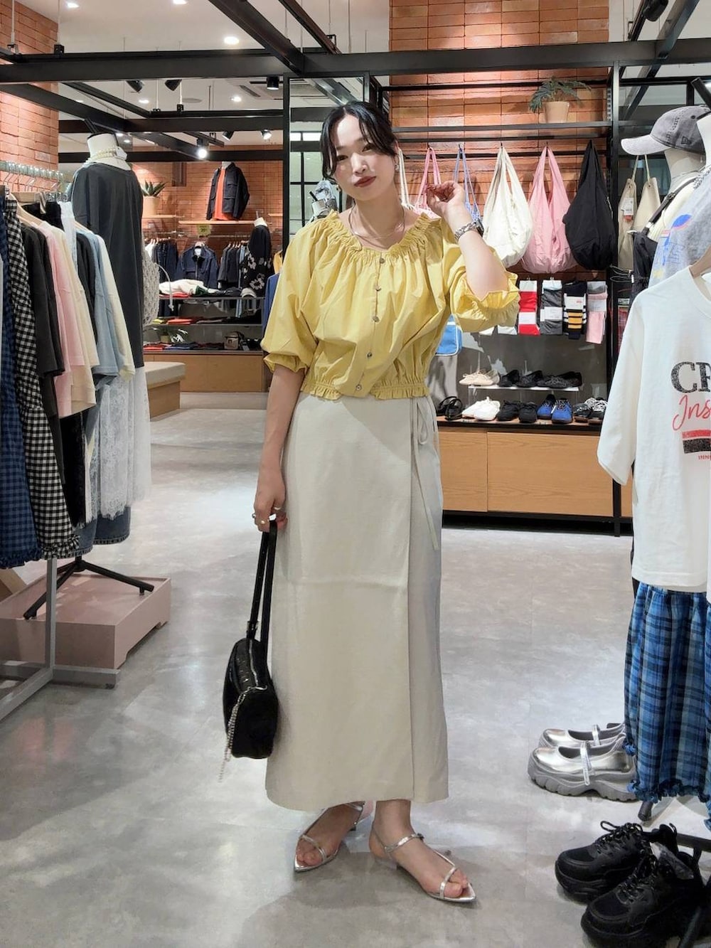 ホワイト系のスカート、ブラック系のトートバッグ、シルバー系のサンダルを着用したレディースの春コーディネートの3枚目の写真