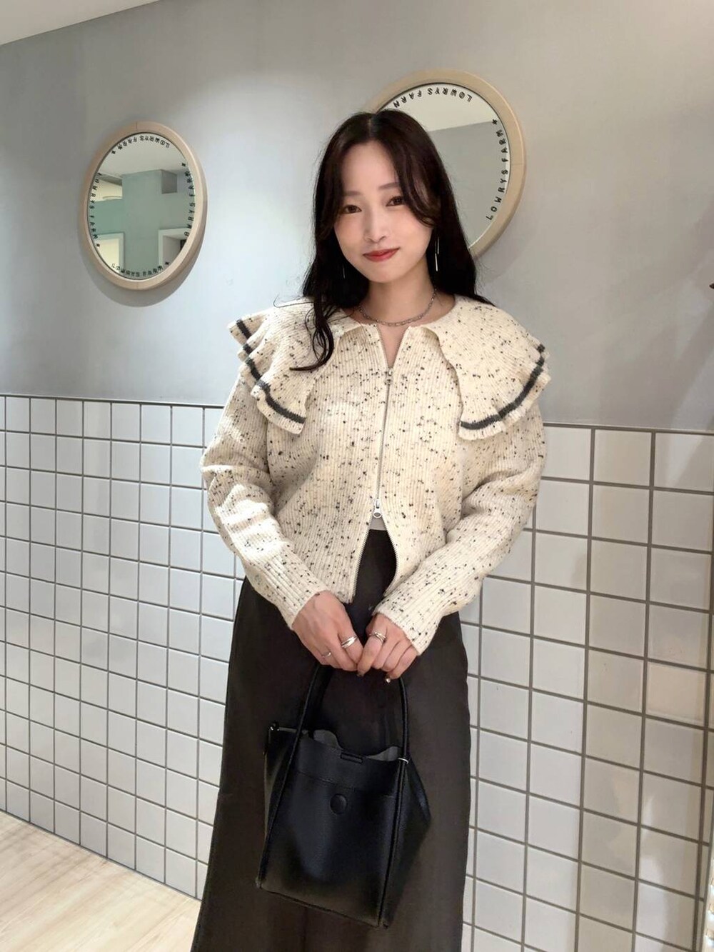 ブラック系のショルダーバッグ、グレー系のスカート、ベージュ系のニット/セーターを着用したレディースの秋コーディネートの4枚目の写真