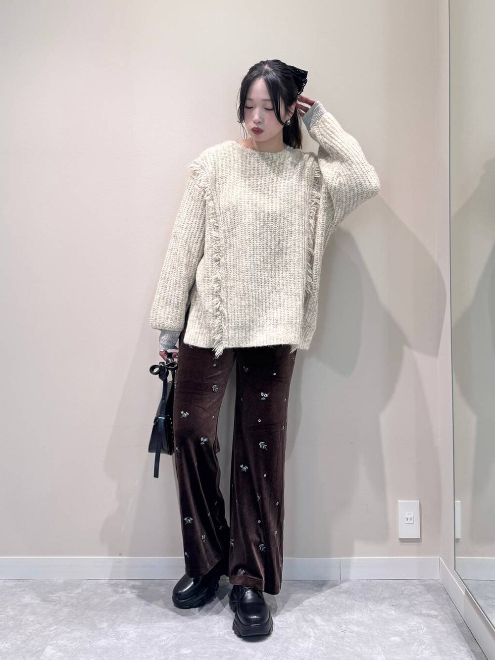 ホワイト系のニット/セーター、ホワイト系のTシャツ/カットソー、ブラック系のショルダーバッグを着用したレディースの冬コーディネートの2枚目の写真