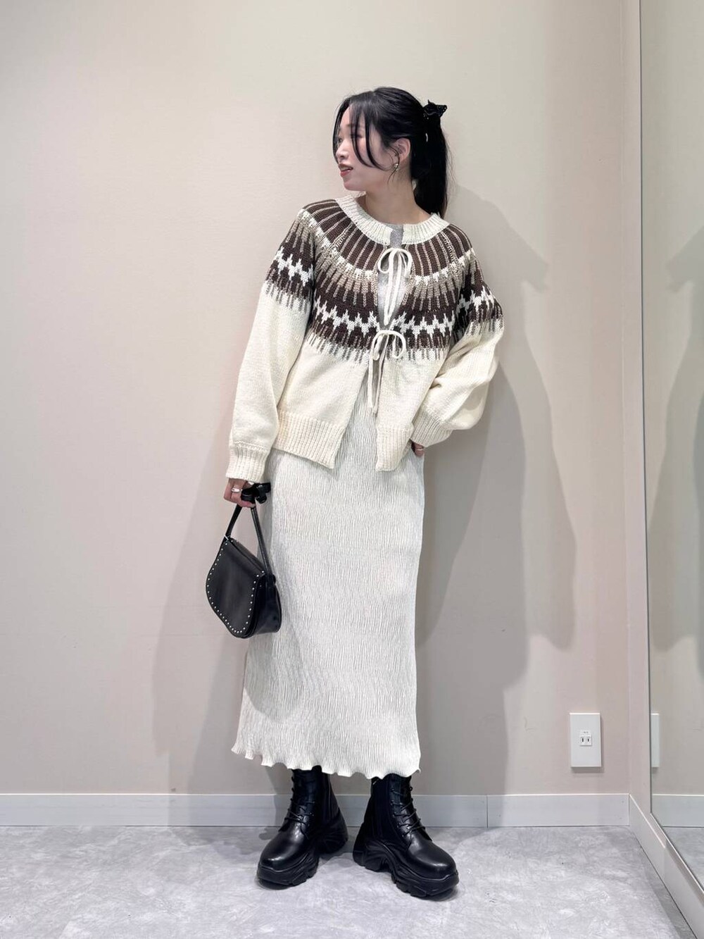 ブラック系のショルダーバッグ、ホワイト系のTシャツ/カットソー、ホワイト系のスカートを着用したレディースの冬コーディネートの2枚目の写真