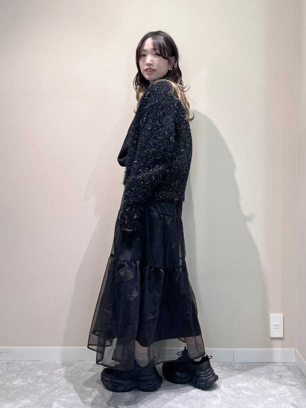 ブラック系のカーディガン/ボレロ、ブラック系のスカート、ブラック系のスニーカーを着用したレディースの冬コーディネートの3枚目の写真