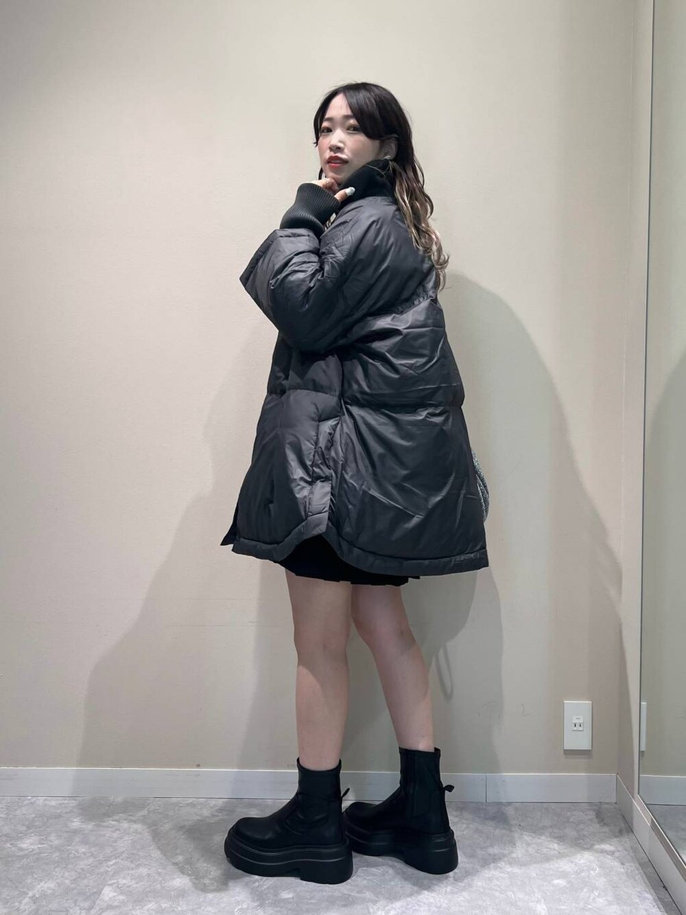 グレー系のポンチョ、シルバー系のショルダーバッグ、ブラック系のブーツを着用したレディースの秋コーディネートの2枚目の写真