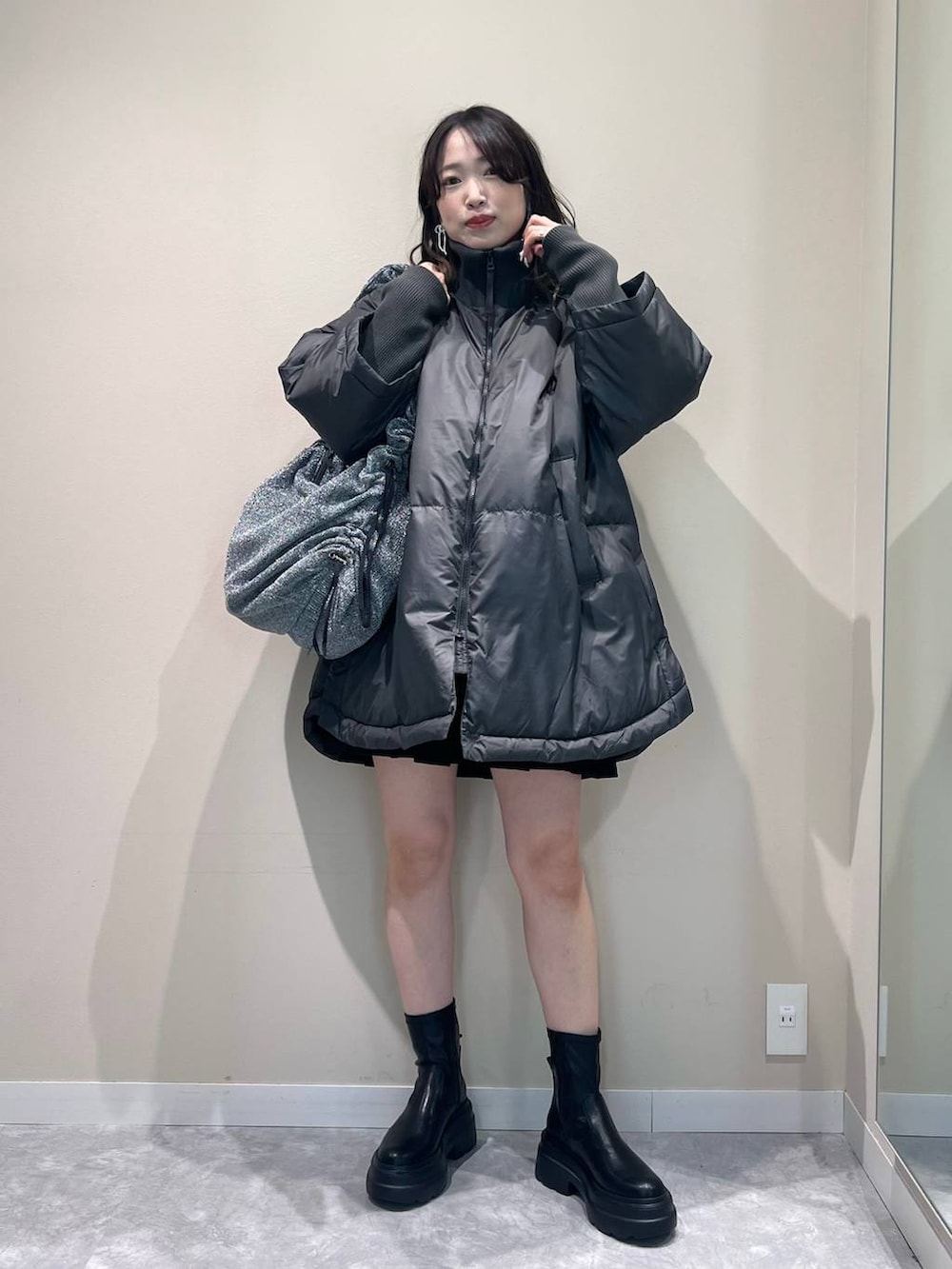 グレー系のポンチョ、シルバー系のショルダーバッグ、ブラック系のブーツを着用したレディースの秋コーディネートの4枚目の写真